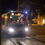 Ein Bus an der Haltestelle nimmt nachts Fahrgäste auf.