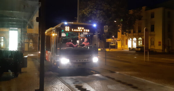 Ein Bus an der Haltestelle nimmt nachts Fahrgäste auf.